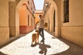 Young Hispanic man with beard and sunglasses waving goodbye to camera with his dog holding on to leash walking along a sunny Royalty Free Stock Photo