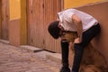 Young Hispanic man with beard, sunglasses and white shirt, leaning against a wall hugging his dog between his legs. Concept Royalty Free Stock Photo