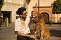 Young Hispanic man with beard, sunglasses and white shirt, sitting on a bench hugging and petting his dog. Concept animals, dogs, Royalty Free Stock Photo