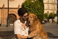 Young Hispanic man with beard, sunglasses and white shirt, sitting on a bench hugging and petting his dog. Concept animals, dogs, Royalty Free Stock Photo