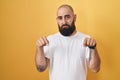 Young hispanic man with beard and tattoos standing over yellow background pointing down looking sad and upset, indicating Royalty Free Stock Photo