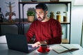 Young hispanic man with beard using computer laptop at night at home depressed and worry for distress, crying angry and afraid Royalty Free Stock Photo