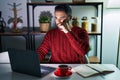 Young hispanic man with beard using computer laptop at night at home mouth and lips shut as zip with fingers Royalty Free Stock Photo