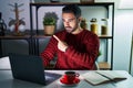 Young hispanic man with beard using computer laptop at night at home pointing with hand finger to the side showing advertisement, Royalty Free Stock Photo