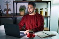 Young hispanic man with beard using computer laptop at night at home relaxed with serious expression on face Royalty Free Stock Photo