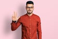 Young hispanic man with beard wearing business shirt and glasses showing and pointing up with fingers number three while smiling Royalty Free Stock Photo