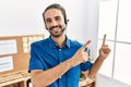 Young hispanic man with beard wearing call center agent headset at the office smiling and looking at the camera pointing with two Royalty Free Stock Photo