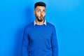 Young hispanic man with beard wearing casual blue sweater making fish face with lips, crazy and comical gesture Royalty Free Stock Photo