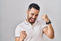 Young hispanic man with beard wearing casual clothes over white background very happy and excited doing winner gesture with arms Royalty Free Stock Photo