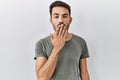 Young hispanic man with beard wearing casual t shirt over white background bored yawning tired covering mouth with hand Royalty Free Stock Photo