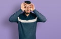 Young hispanic man with beard wearing casual winter sweater doing ok gesture like binoculars sticking tongue out, eyes looking Royalty Free Stock Photo