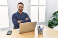 Young hispanic man with beard working at the office with laptop happy face smiling with crossed arms looking at the camera Royalty Free Stock Photo