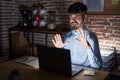 Young hispanic man with beard working at the office at night afraid and terrified with fear expression stop gesture with hands, Royalty Free Stock Photo