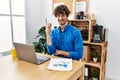 Young hispanic man with beard working at the office using computer laptop with a big smile on face, pointing with hand and finger Royalty Free Stock Photo