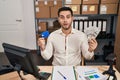 Young hispanic man with beard working at small business ecommerce holding banknotes and credit card afraid and shocked with Royalty Free Stock Photo