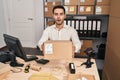 Young hispanic man with beard working at small business ecommerce holding box afraid and shocked with surprise and amazed Royalty Free Stock Photo