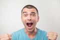 Young hispanic man in blue shirt celebrating victory of his team over gray background Royalty Free Stock Photo