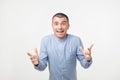 Young hispanic man in blue shirt celebrating victory of his team over gray background Royalty Free Stock Photo