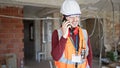 Young hispanic man builder smiling confident talking on smartphone at construction site Royalty Free Stock Photo