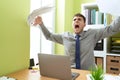 Young hispanic man business worker angry throwing documents screaming at office Royalty Free Stock Photo