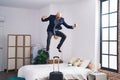 Young hispanic man business worker jumping on bed at hotel room Royalty Free Stock Photo