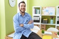 Young hispanic man business worker smiling confident sitting on table with arms crossed gesture at office Royalty Free Stock Photo