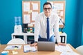 Young hispanic man business worker smiling confident standing by desk at office Royalty Free Stock Photo