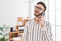 Young hispanic man business worker smiling confident talking on smartphone at office Royalty Free Stock Photo
