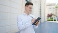 Young hispanic man business worker smiling confident writing on touchpad at hospital Royalty Free Stock Photo