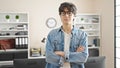 Young hispanic man business worker standing with arms crossed gesture and relaxed expression at office Royalty Free Stock Photo