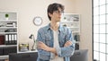 Young hispanic man business worker standing with arms crossed gesture and relaxed expression at office Royalty Free Stock Photo