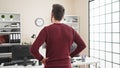 Young hispanic man business worker standing backwards looking clock at office Royalty Free Stock Photo