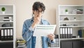 Young hispanic man business worker stressed reading document at office