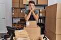 Young hispanic man business worker stressed working at storehouse