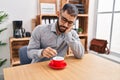 Young hispanic man business worker tired removing coffee at office