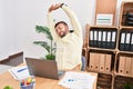 Young hispanic man business worker tired stretching arms at office