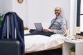 Young hispanic man business worker using laptop sitting on bed at hotel room Royalty Free Stock Photo