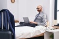 Young hispanic man business worker using laptop sitting on bed at hotel room Royalty Free Stock Photo