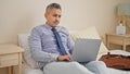 Young hispanic man business worker using laptop sitting on bed at hotel room Royalty Free Stock Photo