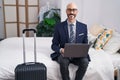 Young hispanic man business worker using laptop sitting on bed at hotel room Royalty Free Stock Photo