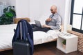 Young hispanic man business worker using laptop sitting on bed at hotel room Royalty Free Stock Photo