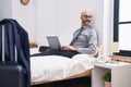 Young hispanic man business worker using laptop sitting on bed at hotel room Royalty Free Stock Photo