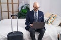 Young hispanic man business worker using laptop sitting on bed at hotel room Royalty Free Stock Photo