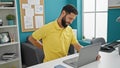 Young hispanic man business worker using laptop suffering for backache at the office Royalty Free Stock Photo