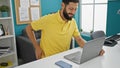 Young hispanic man business worker using laptop suffering for backache at the office Royalty Free Stock Photo