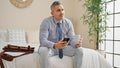 Young hispanic man business worker using smartphone drinking coffee at hotel room Royalty Free Stock Photo