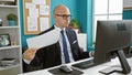 Young hispanic man business worker working suffering for hot using documents as a handfan at the office Royalty Free Stock Photo