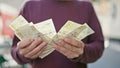 Young hispanic man counting denmark krone banknotes at street