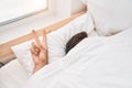 Young hispanic man covering with bedsheet doing victory gesture at bedroom