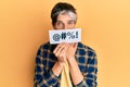 Young hispanic man covering mouth with insult message paper covering mouth with hand, shocked and afraid for mistake